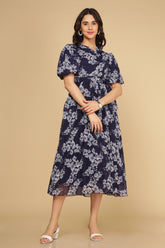 Navy floral pleated maxi dress on a model with sandals.