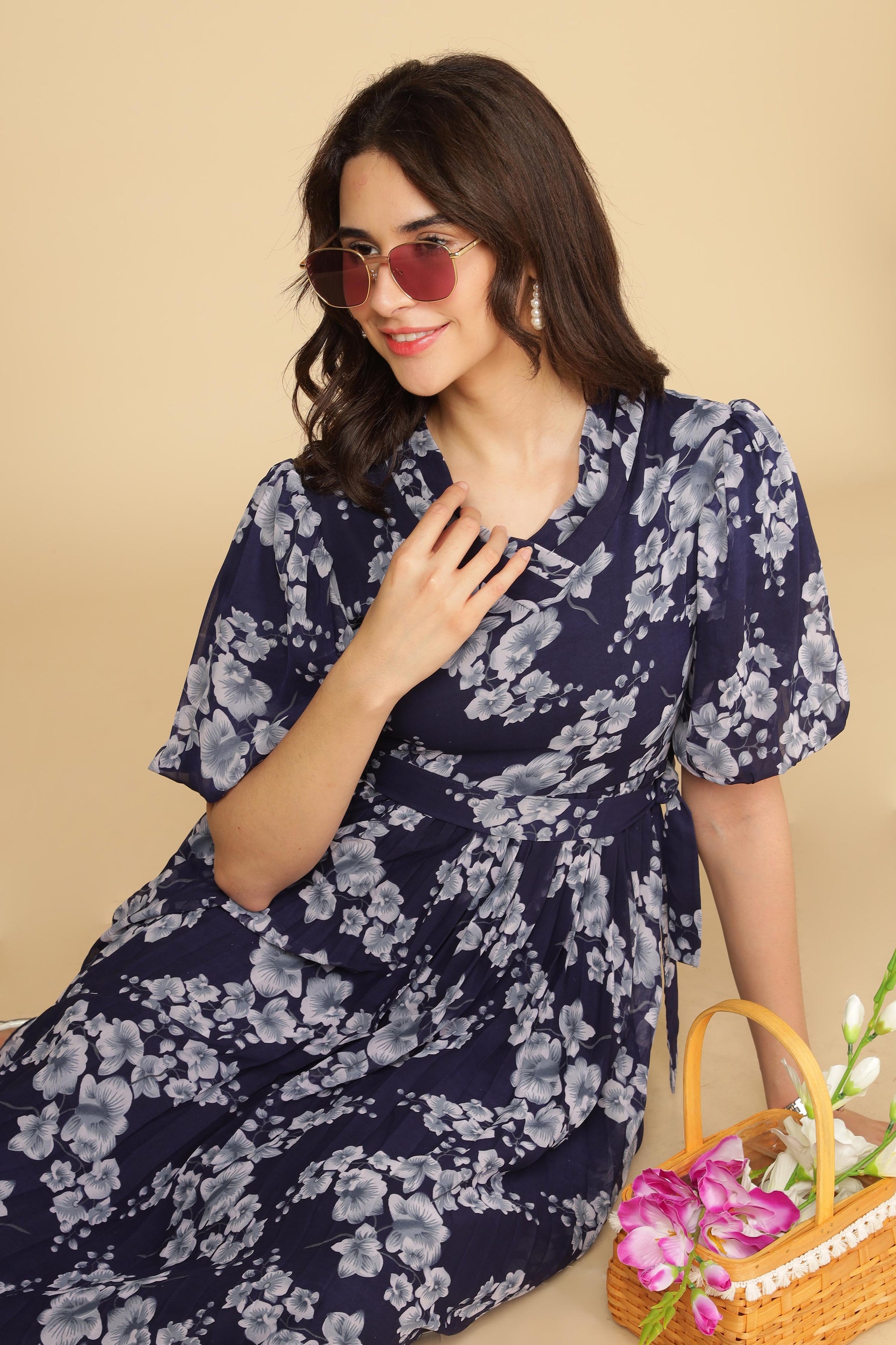 Navy floral pleated maxi dress with stylish sunglasses and flowers.