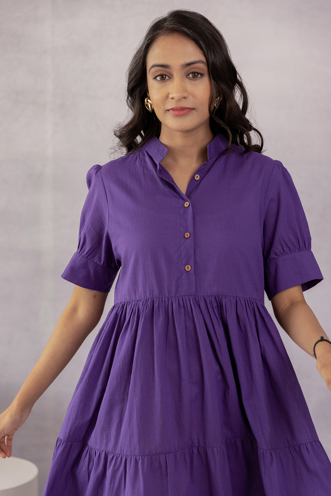 Purple cotton midi dress with button details and puff sleeves.