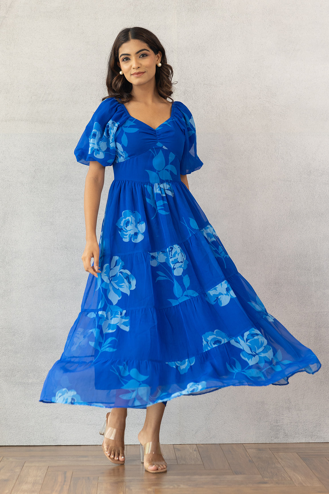 Model wearing a royal blue floral maxi dress on a neutral background.