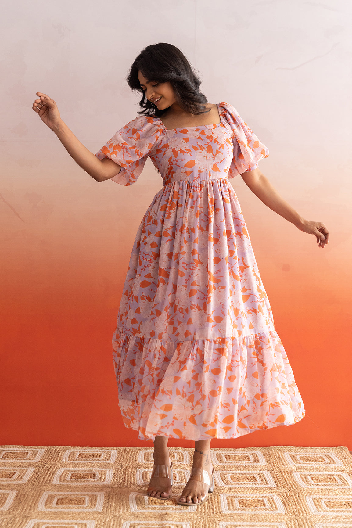 Woman in a pastel maxi dress with floral patterns, showcasing elegance.